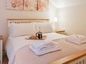 A neatly made bed with a tray of croissant and coffee, a bedside lamp, and a stack of towels. - 2 bedroom accommodation in Liskeard (Liskeard)