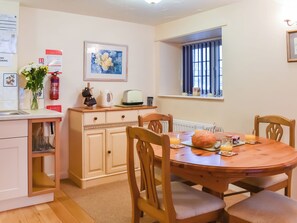 A cozy kitchen with a wooden table, chairs, a toaster, and a vase with flowers. - 2 bedroom accommodation in Liskeard (Liskeard)