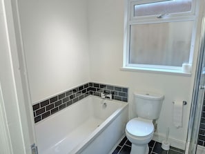 Une salle de bain avec une baignoire, des toilettes et une fenêtre.
