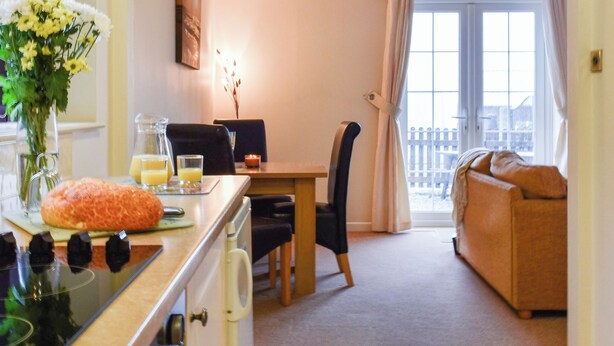 Een gezellige zithoek met een eettafel, stoelen, een bank en een keuken met fornuis.