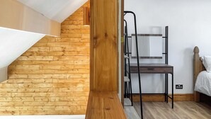 Ein Zimmer mit einer Holztreppe, einer Metallleiter, einem Bett und einer weißen Wand.