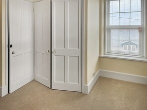 A corner room with a white door, a window with blinds, and beige carpet. - The Farmhouse - UK49068 (Liskeard)