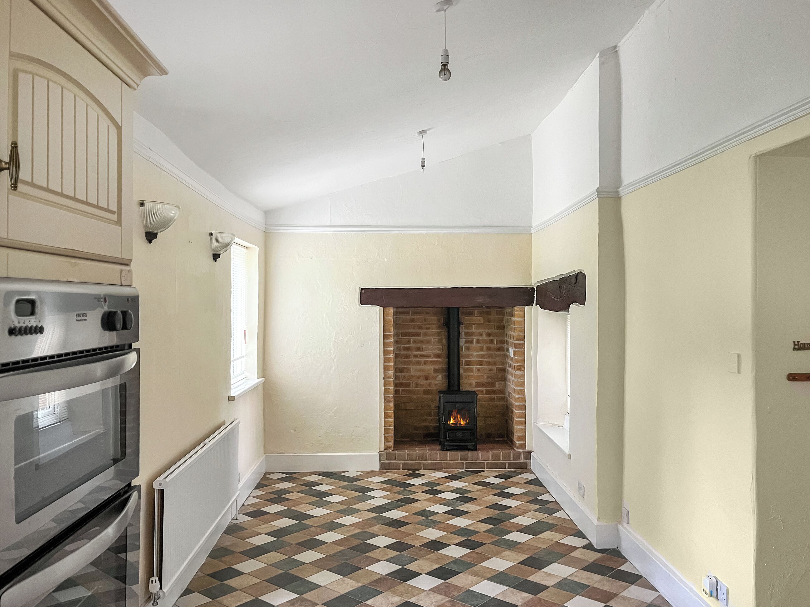 A kitchen with a built-in oven, a stove, and a tiled floor.