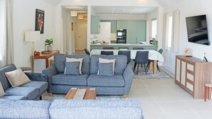 Ein modernes Wohnzimmer mit einer Couch, einem Essbereich und einer Küche im Hintergrund.