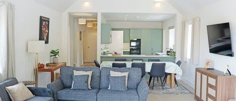 Una sala moderna con un sofá, un comedor y una cocina al fondo.