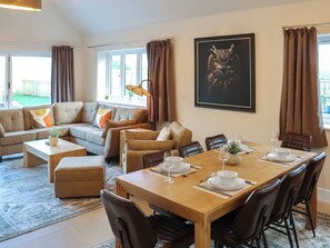 Un salon moderne comprenant un coin repas, un ensemble de canapés, une table basse et une table à manger avec quatre chaises.