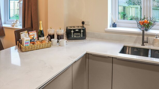 A kitchen with a marble countertop, a toaster, a bottle of champagne, and a basket of bread.