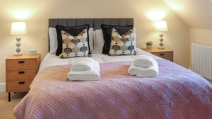A bedroom with a bed, two nightstands, a headboard, and two lamps.