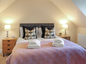 Une chambre à coucher comprenant un lit, deux tables de chevet, une tête de lit et deux lampes.