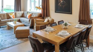A modern living room with a dining area, a sofa set, a coffee table, and a dining table set for four.