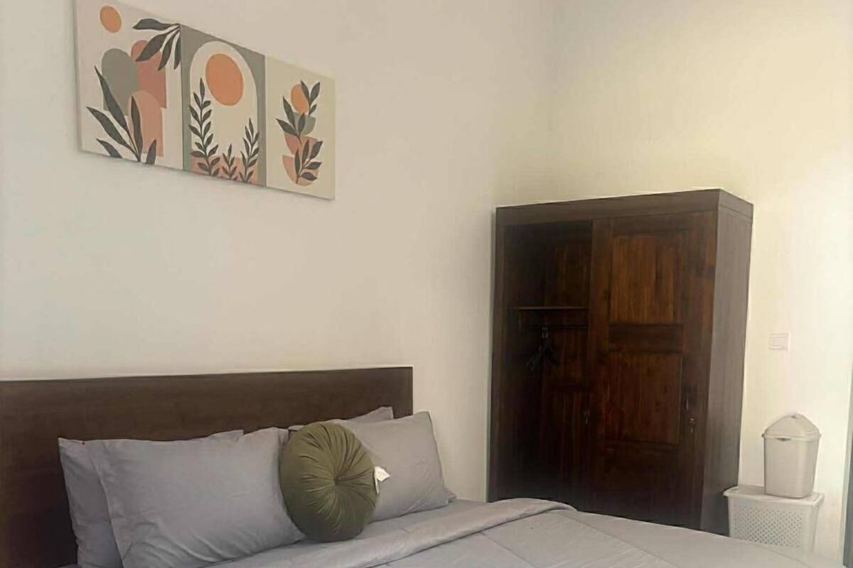 A bedroom with a bed, a wardrobe, and a wall-mounted artwork.