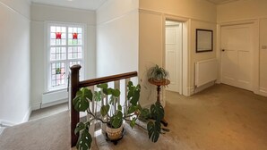 A hallway with a staircase, a potted plant, a door, and a radiator.