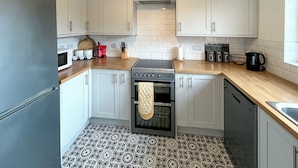 A compact kitchen with white cabinets, a built-in oven, a microwave, and a coffee maker.