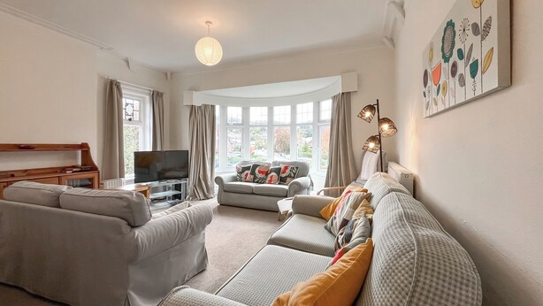 A living room with a sofa, a television, and a window with curtains.
