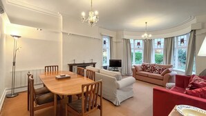 A spacious living area with a wooden dining table, a sofa, and a red armchair.