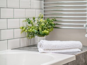 A bathroom with white tiles, a towel, and a plant. - Lovely cottage in the heart of Llandeilo - perfect for a romantic break away. (Llandeilo)