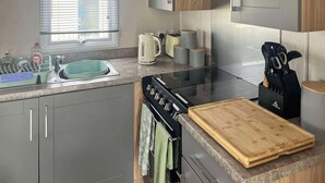 A modern kitchen with a sink, stove, and wooden countertop. - 3 bedroom accommodation in New Quay (New Quay)