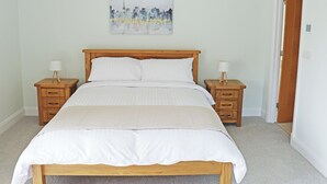 Een slaapkamer met een houten bed, twee nachtkastjes, een wanddecoratie en een deur.