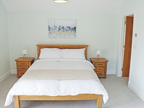 Ein Schlafzimmer mit einem hölzernen Bett, zwei Nachttischen, einem Wandbild und einer Tür.