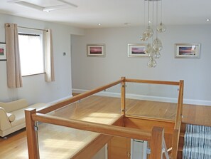 Ein modernes Wohnzimmer mit Glastrennwand, Holzboden, einer Couch und Kunstwerken an den Wänden.