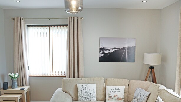 Een woonkamer met een bank, een salontafel, een lamp en een raam met gordijnen.