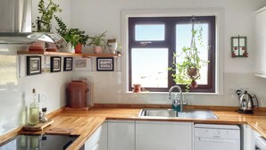 Cucina con piani in legno, lavastoviglie integrata, lavello e finestra con vista.