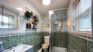 A bathroom with a glass-enclosed shower, a toilet, and a sink with a cabinet. - 1 bedroom accommodation in Abergele (Abergele)