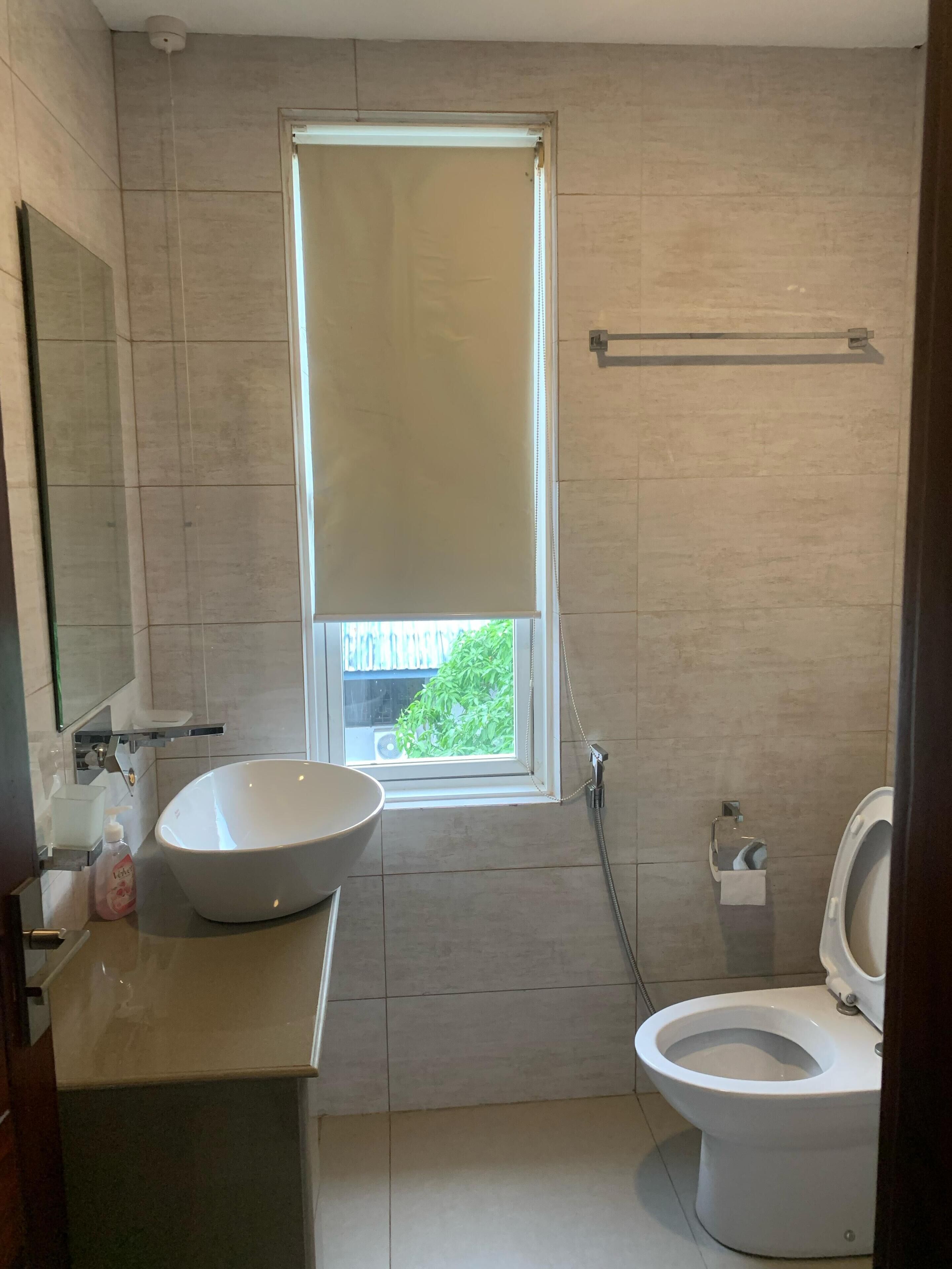 A bathroom with a large window, a sink, a toilet, and a shower.