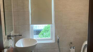 A bathroom with a large window, a sink, a toilet, and a shower.