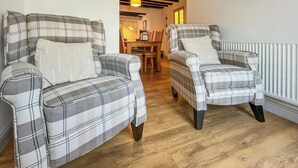 Two plaid armchairs with cushions in a room with wooden flooring and a radiator. - 4 bedroom accommodation in Beaumaris (Beaumaris)
