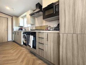 Eine moderne Küche mit integriertem Wasch- und Trockner, Holzschränken und einer Mikrowelle.