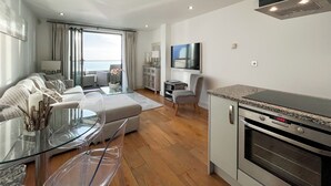 Una sala de estar moderna con un sofá, una mesa de centro de vidrio y un televisor.