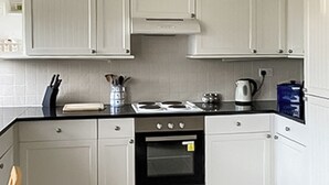 Eine Küche mit weißen Schränken, einem Herd, einem Backofen und einer Kaffeemaschine.