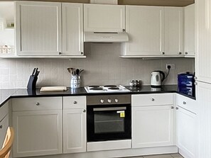 A kitchen with white cabinets, a stove, an oven, and a coffee maker. - 2 bedroom accommodation in Althorne, near Chelmsford (Althorne, near Chelmsford)