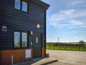 A two-story building with a dark exterior, a brick base, and a black door. - 2 bedroom accommodation in Althorne, near Chelmsford (Althorne, near Chelmsford)