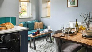 A cozy kitchen with a dining area, a teal sofa, and a window with a view of greenery. - 3 bedroom accommodation in Llandundo Junction (Llandundo Junction)