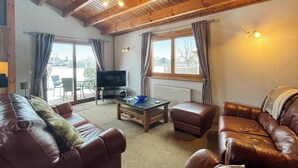 Ein geräumiges Wohnzimmer mit Ledersofas, einem Couchtisch und einem Fernseher.