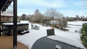 Ein überdachter Außenbereich mit Whirlpools, einer Terrasse und einem schneebedeckten Garten.
