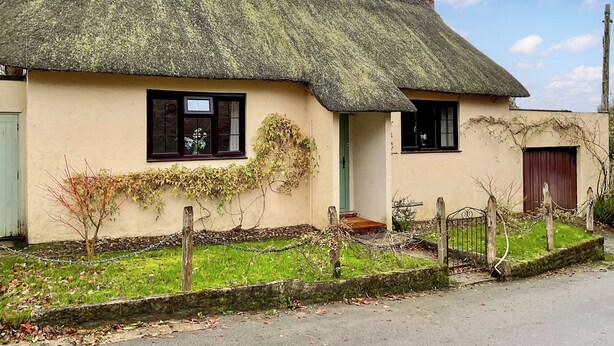 A traditional thatched-roof house with a green door, a small window with a flower box, and a sign reading "Schoolhouse". - 3 bedroom accommodation in Ibberton, near Blandford Forum (Ibberton, near Blandford Forum)