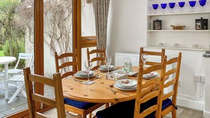 A dining area with a wooden table set for four, surrounded by wooden chairs with blue cushions. - 3 bedroom accommodation in Ibberton, near Blandford Forum (Ibberton, near Blandford Forum)
