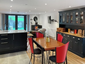 A modern kitchen with a central island, red chairs, black cabinets, and a visible stove.