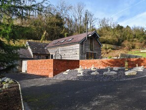 Ein zweistöckiges Holzhaus mit einer Backsteinmauer, einem Schotterweg und einem eingezäunten Garten.