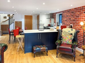 Een moderne keuken met een centraal eiland, houten vloeren en een accentmuur van baksteen.