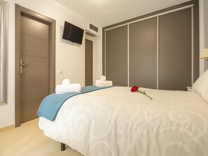 A bedroom with a bed, a TV mounted on the wall, a wardrobe, and a bedside table. - Bungalow Cristina in Estepona (Estepona)