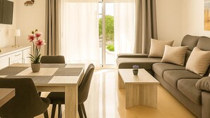 Ein modernes Wohnzimmer mit Sofa, Couchtisch, Esstisch, Stühlen und einer Topfpflanze.