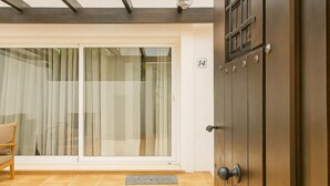 Ein Zimmer mit einer Schiebeglastür, einer Holztür mit runder Klinke und einem Fliesenboden.