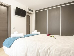 A hotel room with a bed, a TV mounted on the wall, and a wardrobe with sliding doors. - Bungalow Cristina in Estepona (Estepona)
