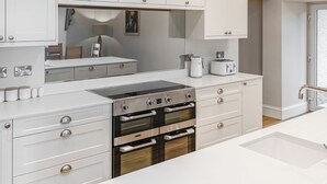 A modern kitchen with white cabinetry, stainless steel appliances, and a built-in oven.
