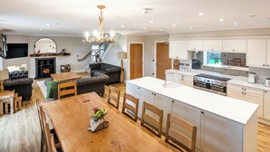 A modern kitchen with a central island, wooden dining table, and built-in appliances.