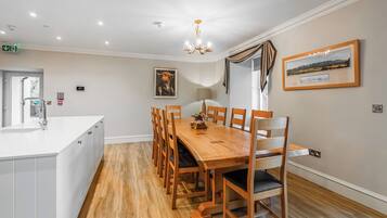 A dining area with a wooden table and chairs, a chandelier, and a framed picture on the wall.